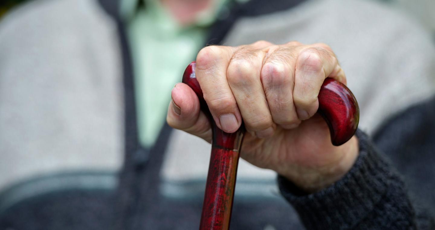 Elderly hand holding wood cane