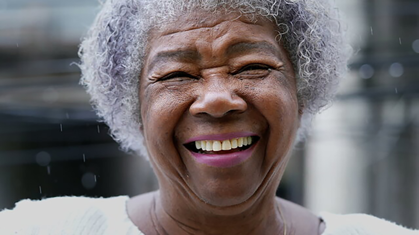 older black woman with grey hair smiling.