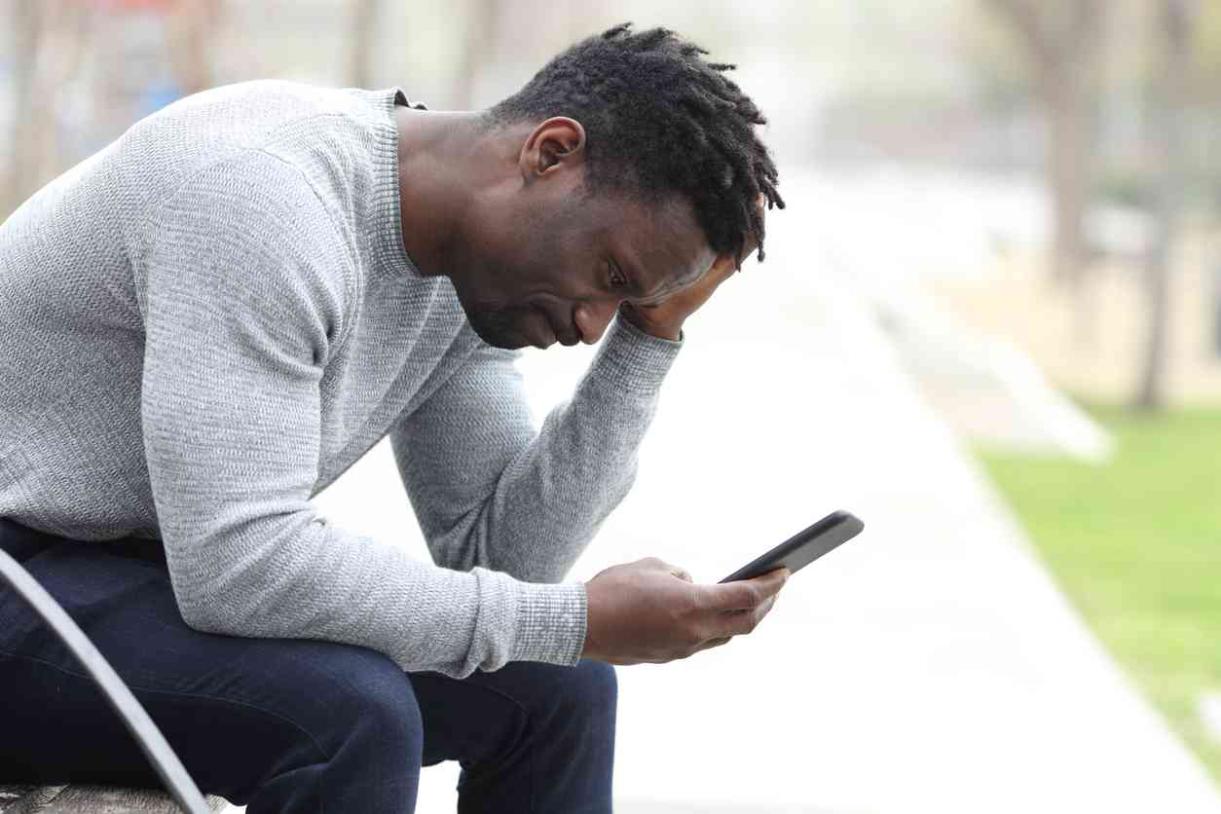 black man with gray sweater looking at phone
