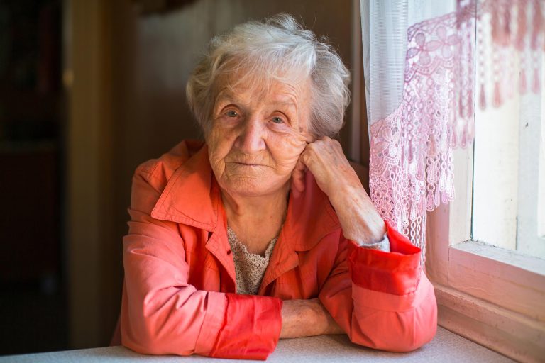 older woman at table looking into camera