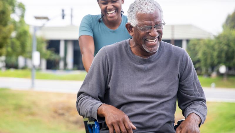 Black woman pushing Black man in wheelchair.