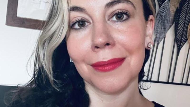 A woman with red lipstick and a blond streak in her hair.