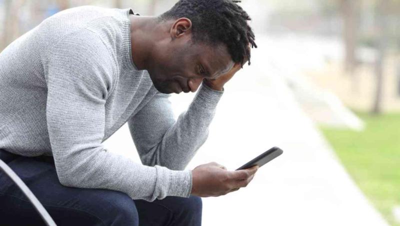 black man with gray sweater looking at phone