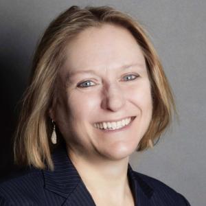 A smiling woman in a dark blue blazer.