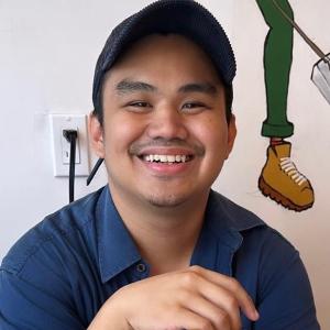 A man with a blue shirt and cap on. He's smiling.